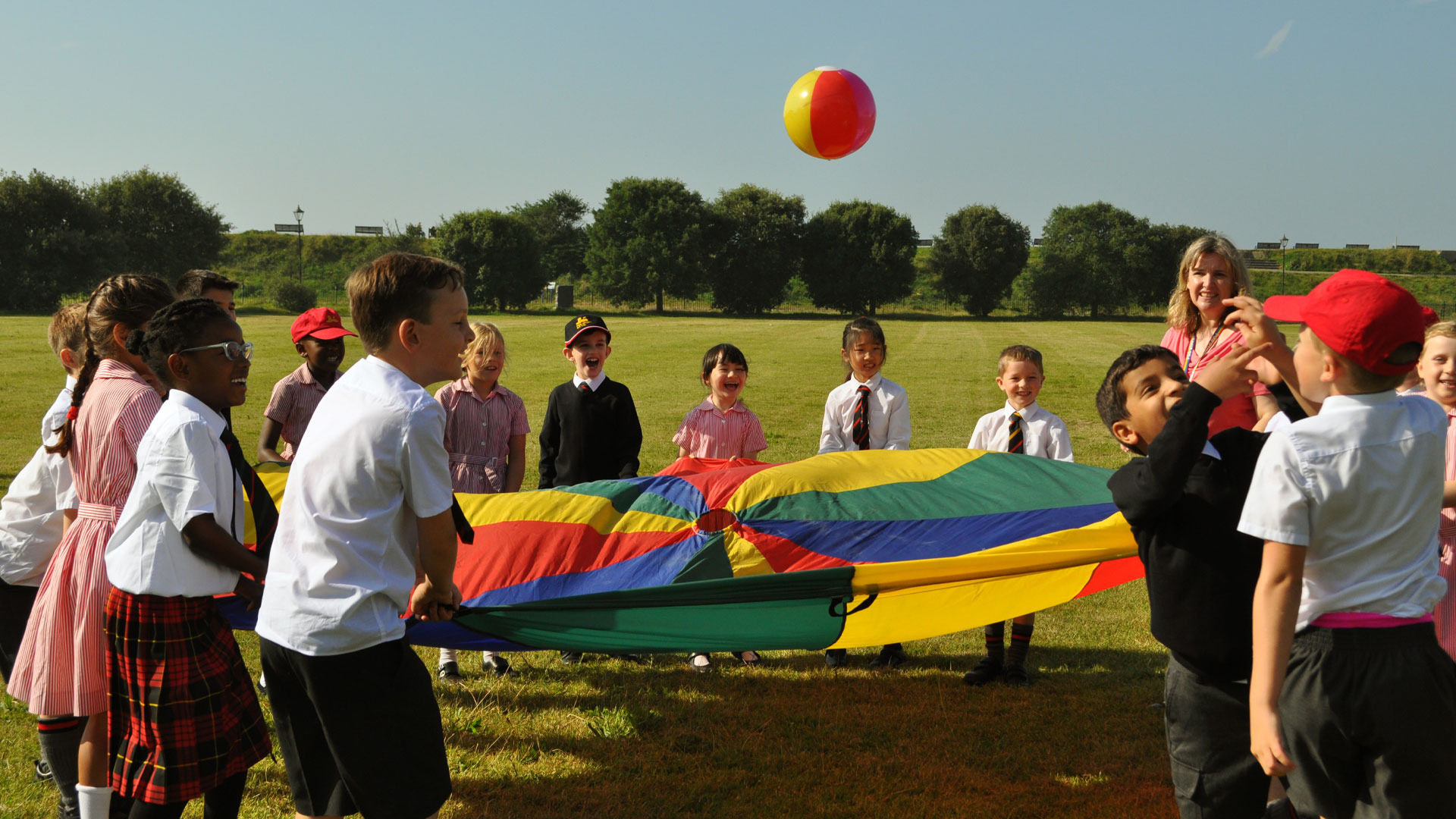 Junior PGS students playing outdoors with a parachute
